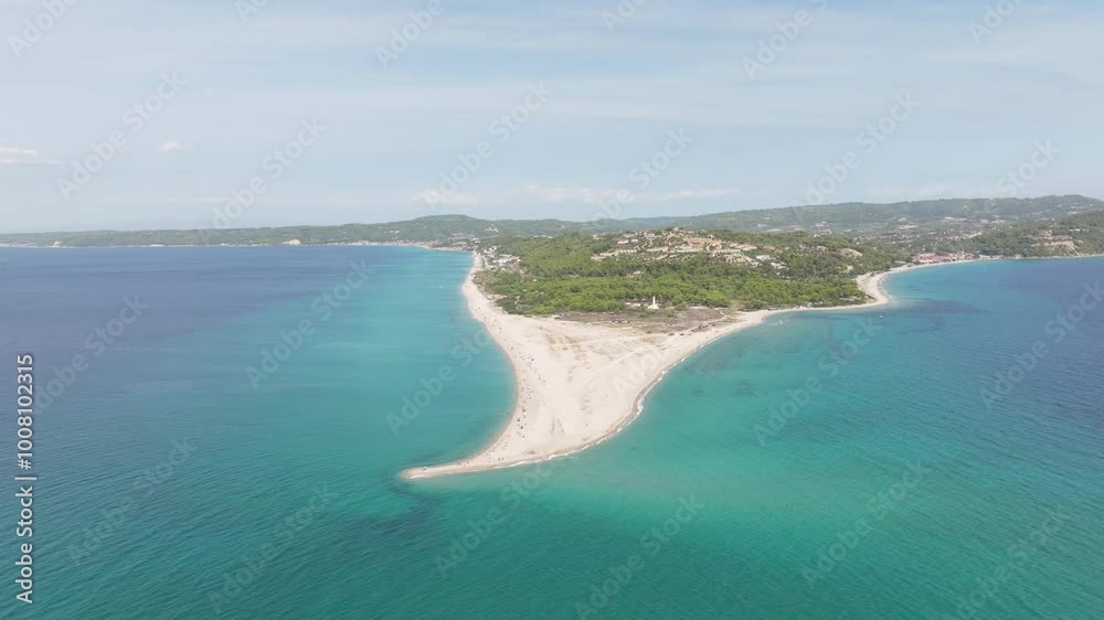 Aerial view of the narrow sandy peninsula at Possidi Cape, Greece, surrounded by turquoise waters and lush greenery under a bright, clear sky.