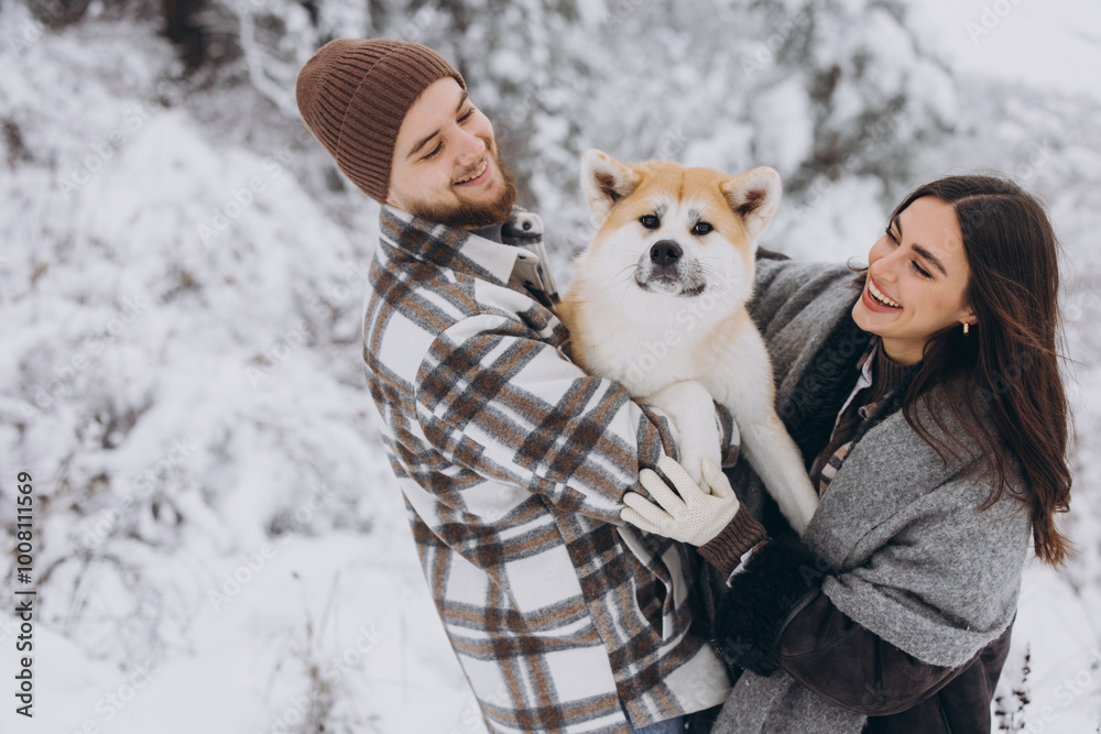 Happy young couple with akita dog in forest on winter day Happy young couple with akita dog in forest on winter day