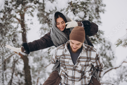 A young happy and loving couple is having fun in a snowy forest in winter. photo