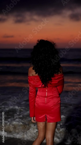 An African woman gracefully poses on the ocean shore at sunset, radiating beauty and confidence. This enchanting scene captures the essence of travel and style, perfect for lifestyle projects.