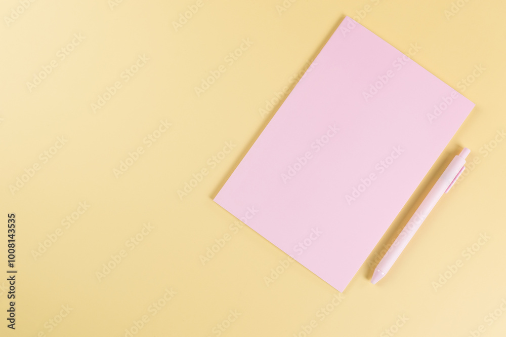 Top view of pink notebook, pink pen on yellow background. School, office wallpaper. Flat lay, copy space. Top view of pink notebook, pink pen on yellow background. School, office wallpaper. Flat lay, copy space.