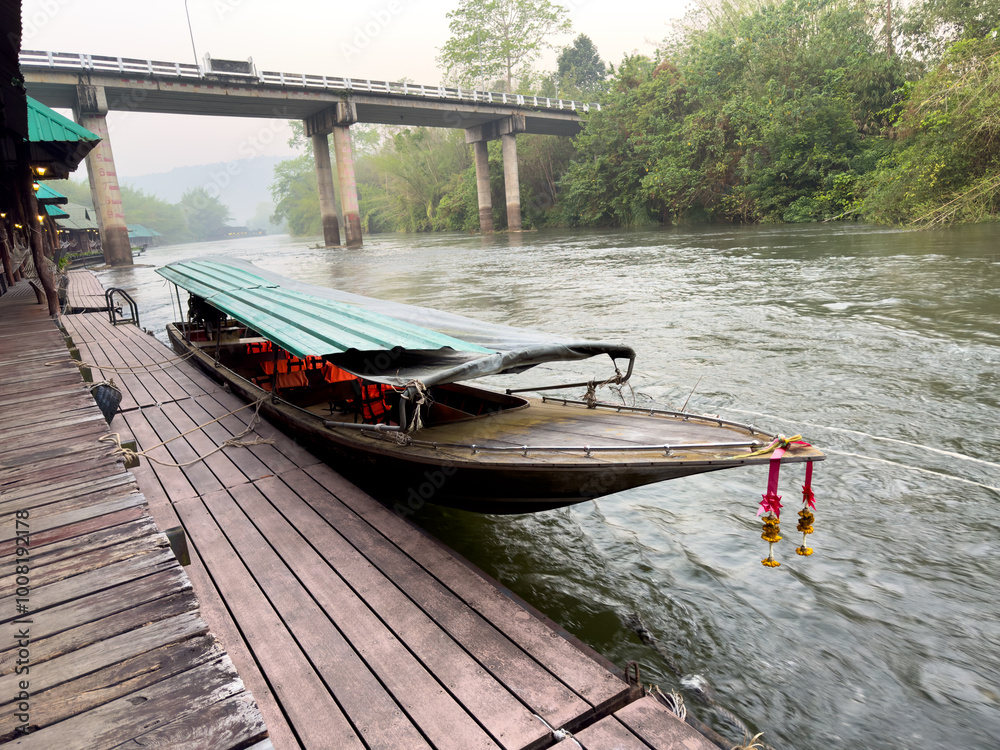 Fototapeta premium A boat is docked at a pier with a bridge in the background