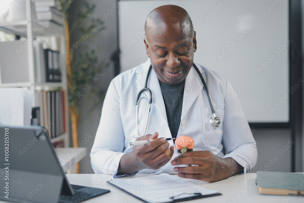 Smiling doctor is sitting at his desk holding an anatomical model of a human brain while explaining something during a consultation Smiling doctor is sitting at his desk holding an anatomical model of a human brain while explaining something during a consultation