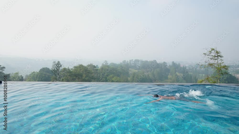 A Man Swimming In Infinity Pool With Golf Court View Below A Man Swimming In Infinity Pool With Golf Court View Below