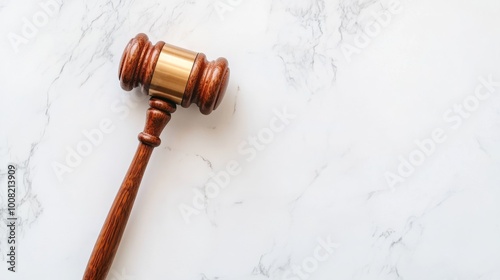 A wooden judge's gavel rests on a plain white surface. photo