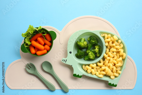 Cute elephant-themed baby feeding set with healthy food on blue background. photo