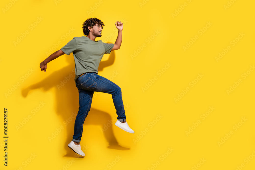 Full size photo of overjoyed nice guy dressed khaki t-shirt jeans running look at promo empty space isolated on yellow color background Full size photo of overjoyed nice guy dressed khaki t-shirt jeans running look at promo empty space isolated on yellow color background
