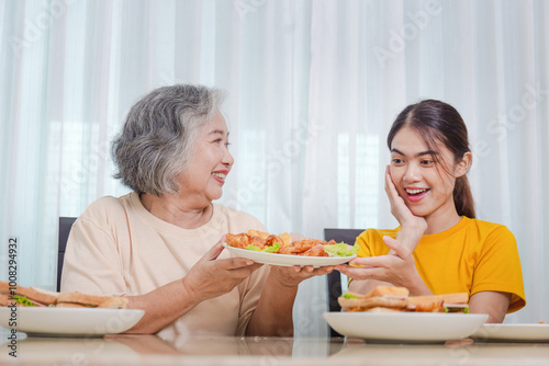 Mother and adult daughter eating meal together, Senior woman and daughter having breakfast in morning together