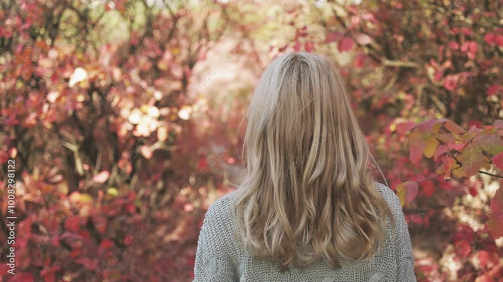 Attractive young blonde woman in a gray sweater and black skirt walks through the autumn park and enjoys the warm autumn weather Attractive young blonde woman in a gray sweater and black skirt walks through the autumn park and enjoys the warm autumn weather