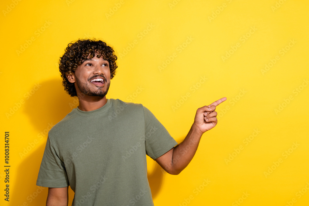 Photo of positive guy with curly hairstyle dressed khaki shirt indicating look at logo empty space isolated on yellow color background Photo of positive guy with curly hairstyle dressed khaki shirt indicating look at logo empty space isolated on yellow color background