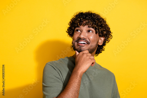 Photo of positive smart guy with stubble curly hairstyle dressed khaki shirt look at offer empty space isolated on yellow color background