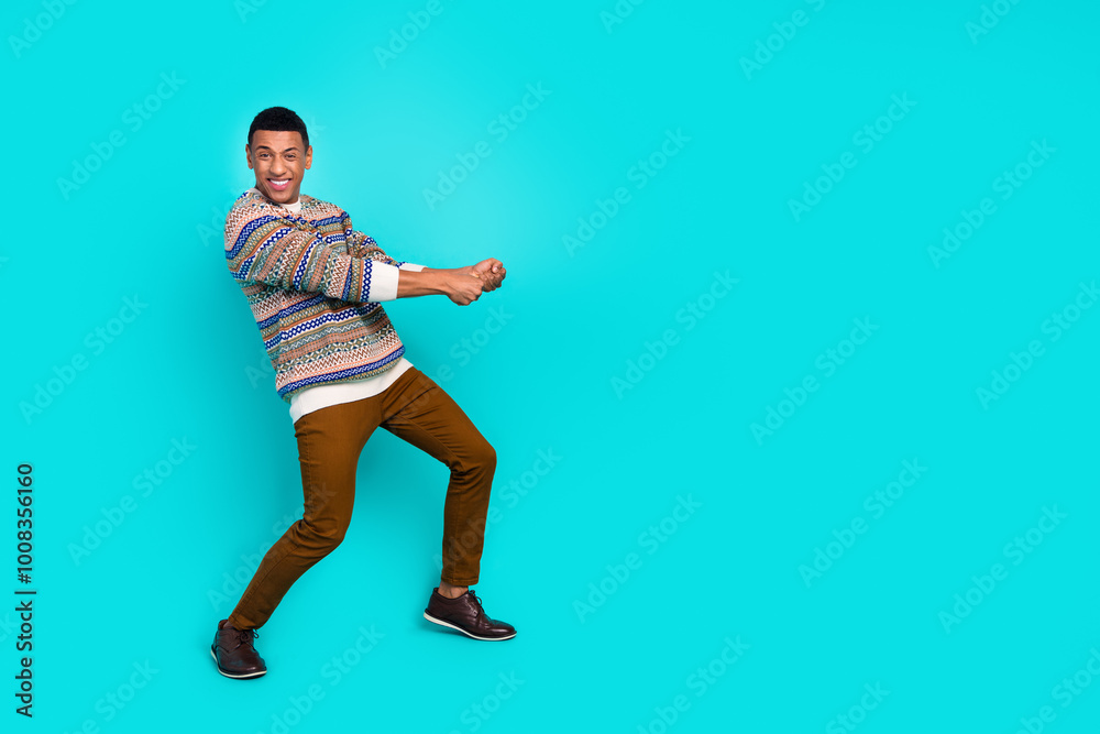 Full body portrait of nice young man pull empty space rope wear pullover isolated on turquoise color background Full body portrait of nice young man pull empty space rope wear pullover isolated on turquoise color background