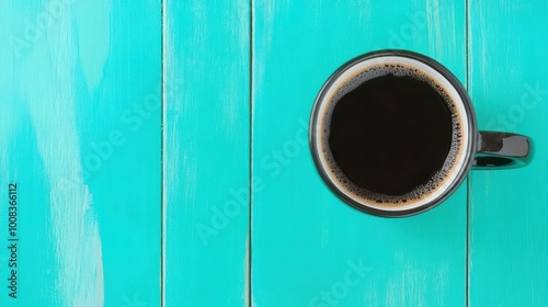 Top view of black coffee in cup on turquoise wooden background