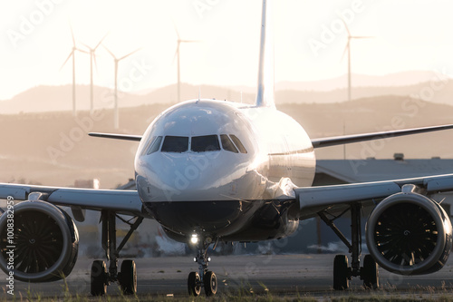 Passenger airplane at airport runway with wind turbines in background. Larnaca, Cyprus
