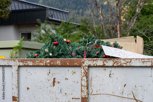 Fotografija Discarded plastic fir trees decorated with red Christmas balls in a trash contai