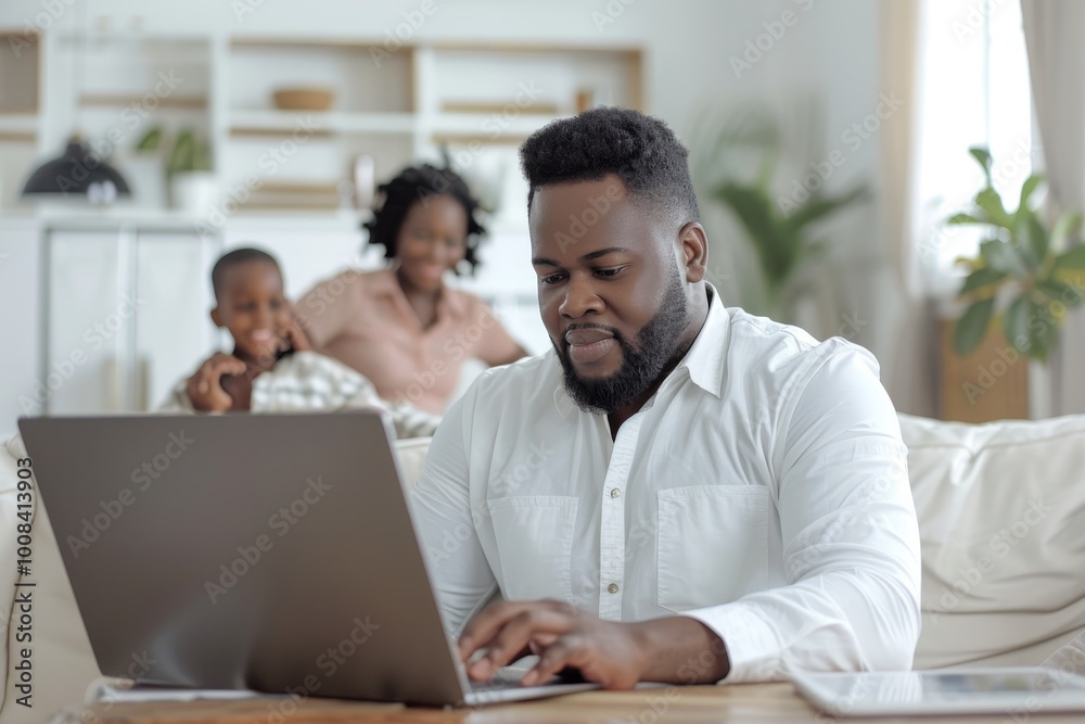 Obraz premium remote work at home, black man is sitting working at laptop, businessman, family is in the background, freelancer