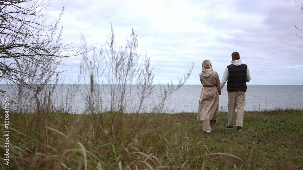 A couple enjoys a delightful and peaceful stroll along the ocean, fully surrounded by natures stunning beauty A couple enjoys a delightful and peaceful stroll along the ocean, fully surrounded by natures stunning beauty