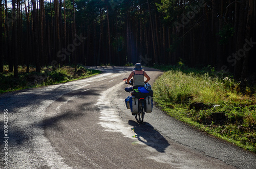 Woman traveling alone on a bicycle on roads and dirt roads surrounded by mountains and forests discovering natural environments. 