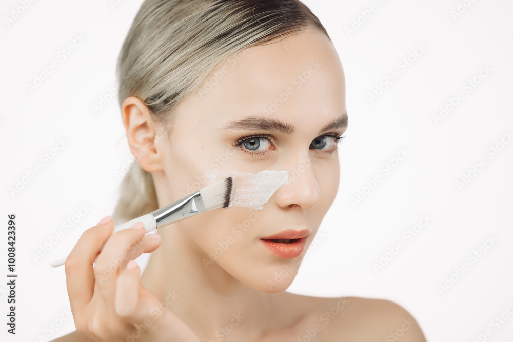 A young woman gently applies cream to her face with a brush. This tender touch emphasizes the importance of skincare and self-care, creating an atmosphere of relaxation and harmony. A young woman gently applies cream to her face with a brush. This tender touch emphasizes the importance of skincare and self-care, creating an atmosphere of relaxation and harmony.