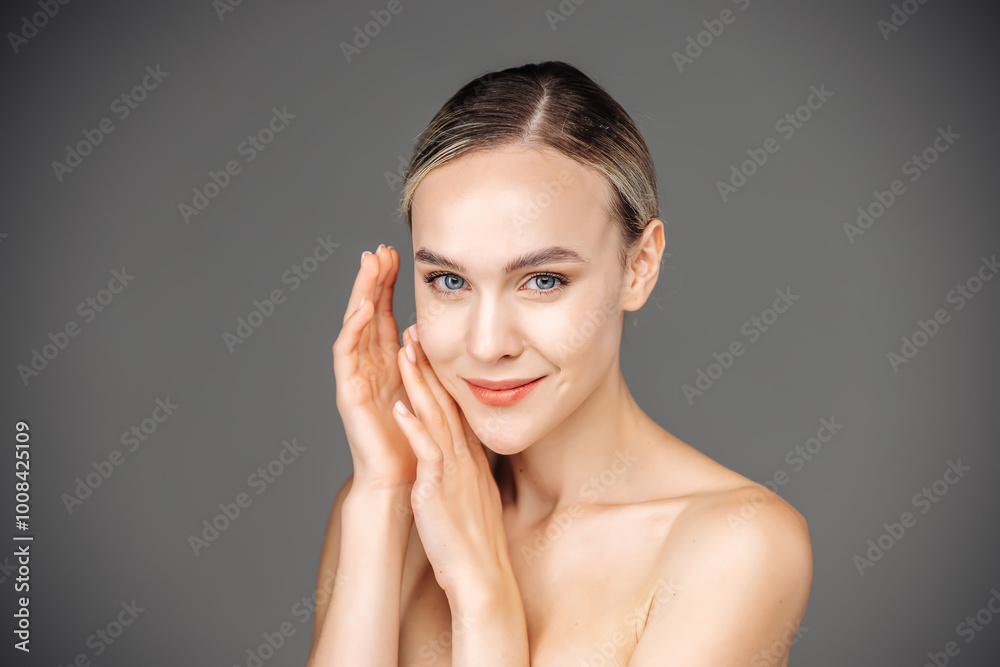 A young woman with radiant skin stands against a dark backdrop, showcasing her natural nude makeup. Her tender touch to her face emphasizes the importance of self-care and beauty. A young woman with radiant skin stands against a dark backdrop, showcasing her natural nude makeup. Her tender touch to her face emphasizes the importance of self-care and beauty.