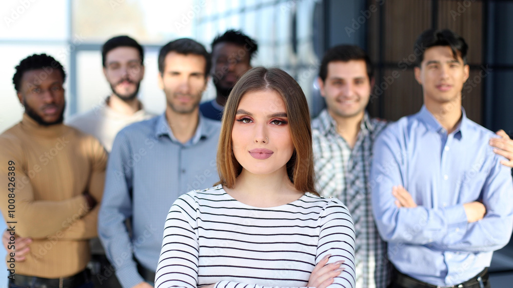 young woman posing for the camera in front of her team in the office young woman posing for the camera in front of her team in the office