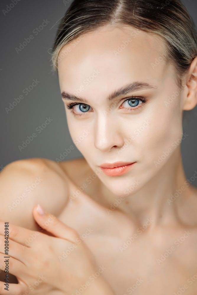 Naklejka premium A beautiful young woman with clean, fresh skin is set against a dark background. The close-up highlights her healthy complexion and the significance of skincare in cosmetology and spa treatments.