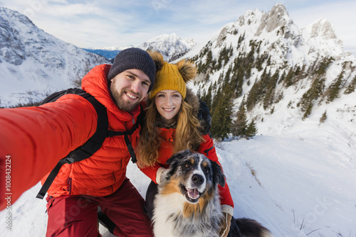 Hiker couple with a dog takes a selfie from a snowy landscape in the winter mountains photo