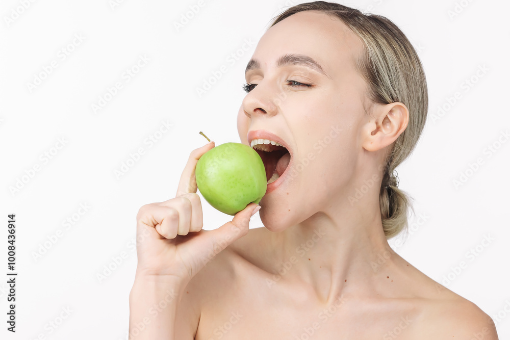 A woman with healthy teeth bites into a green apple against a white background. This shot emphasizes the importance of dental care and health, associating freshness and naturalness with a bright smile A woman with healthy teeth bites into a green apple against a white background. This shot emphasizes the importance of dental care and health, associating freshness and naturalness with a bright smile