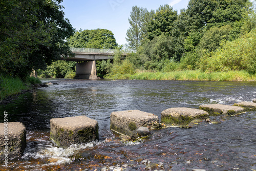 Stepping Stones and Beam and slab concrete road bridge with metal railings over River Ayr on A77 town bypass photo