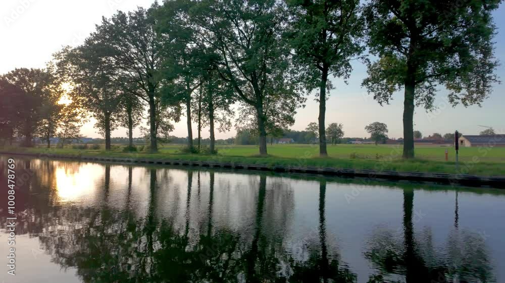 A serene canal scene at sunset, showcasing tree reflections, perfect for themes of nature and tranquility A serene canal scene at sunset, showcasing tree reflections, perfect for themes of nature and tranquility