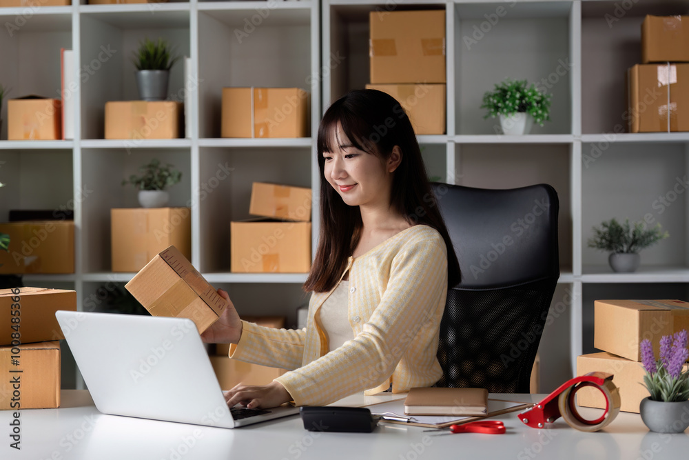Young Woman Checking Customer Order Online for Her E-commerce Business Surrounded by Shipping Boxes Young Woman Checking Customer Order Online for Her E-commerce Business Surrounded by Shipping Boxes