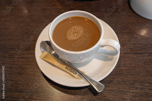 Coffee white cup and saucer served with teaspoon and demerara sugar packet photo