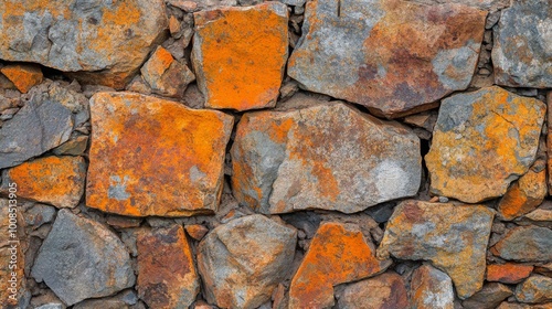 A close-up of a rustic stone wall with orange and grey stones.