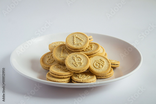round cookies with various designs on them, including Christmas themed symbols like trees, snowmen, and other festive characters. vanilla or butter flavored sandwich cookies.