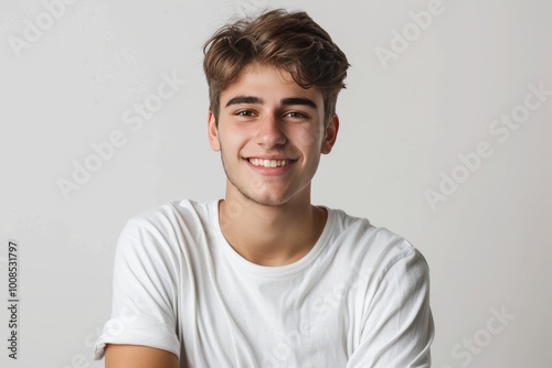 Young male model with a charming smile and crossed arms against a pure white backdrop , background blur