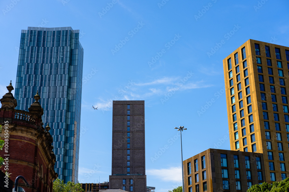 Leeds England: 2nd Jun 2024: Leeds City Skyline Modern architecture under a clear blue sky with a aeroplane flying over urban buildings