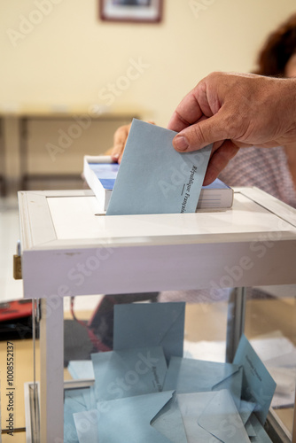 Vue d'une main d'un homme déposant son bulletin de vote dans l'urne lors d'une élection dans un bureau de vote en France.
