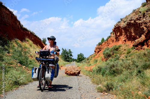 Woman traveling alone on a bicycle on roads and dirt roads surrounded by mountains and forests discovering natural environments. 