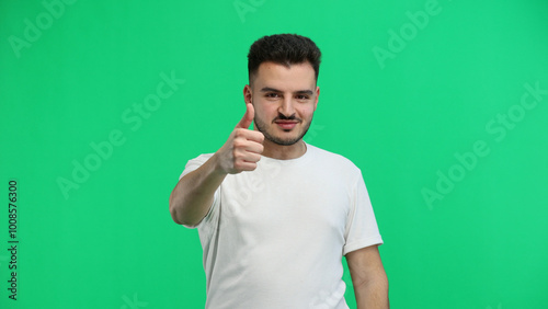 A man, close-up, on a green background, shows a thumbs up