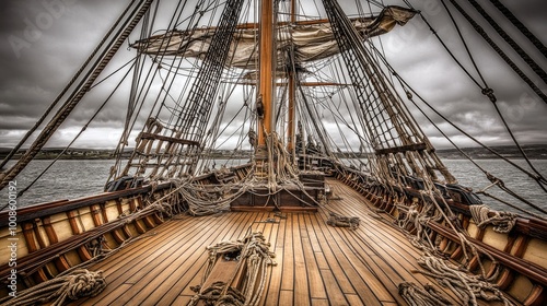 A pirate ship deck with towering masts and ropes hanging down, the wooden planks creaking underfoot as the sea breeze moves through the sails, perfect for a theater scene.