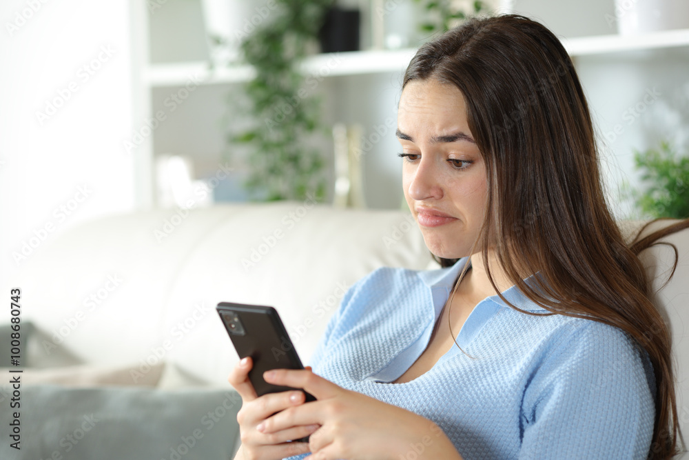 Disappointed woman is checking smart phone at home Disappointed woman is checking smart phone at home