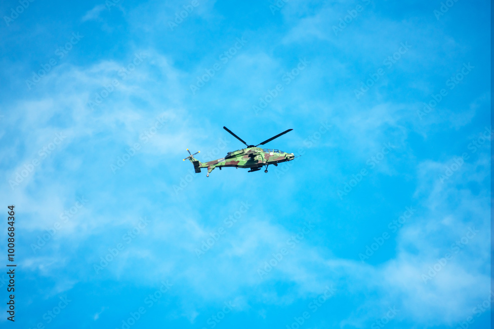 Helicopter is flying on isolated blue sky in mid-air background.