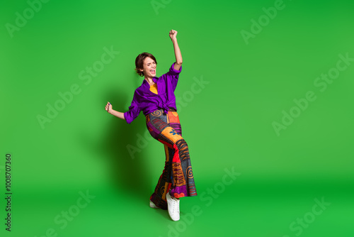 Photo of overjoyed young funky positive girlfriend wearing nostalgia outfit raised arms up shouting isolated on green color background photo