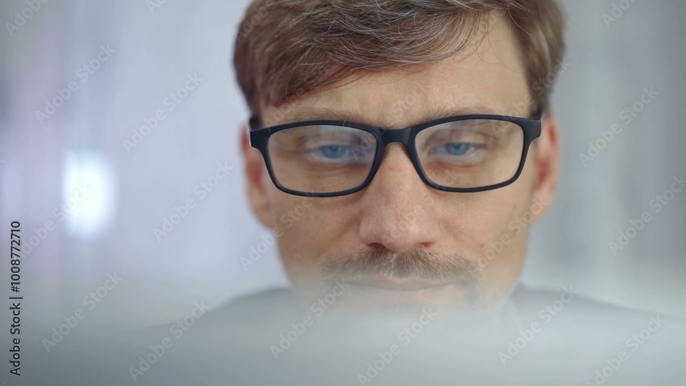 Businessman with glasses looking intently obscured partially by a translucent surface of laptop. Business concept Businessman with glasses looking intently obscured partially by a translucent surface of laptop. Business concept