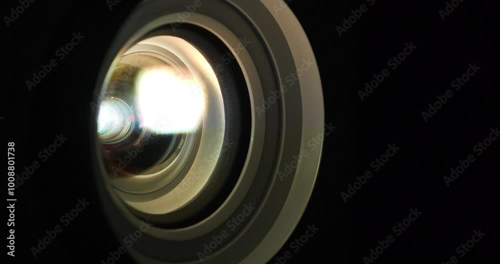 Projector lens in operation close-up. Cinema hall. Lenses of working projector change color. Movie is shown through projector. Light of different colors passes through the lenses Projector lens in operation close-up. Cinema hall. Lenses of working projector change color. Movie is shown through projector. Light of different colors passes through the lenses