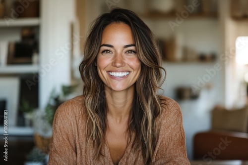 Beaming with joy, a woman in a tan sweater sits comfortably in a warmly illuminated room, evoking a sense of contentment and tranquility.