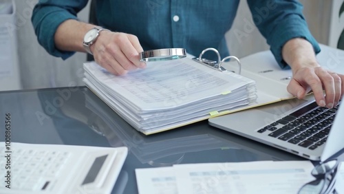 Businessman or professional auditor is analyzing data sheets. Close-up of an bookkeeper's hand with magnifying glass inspecting financial reports. Business audit and taxes