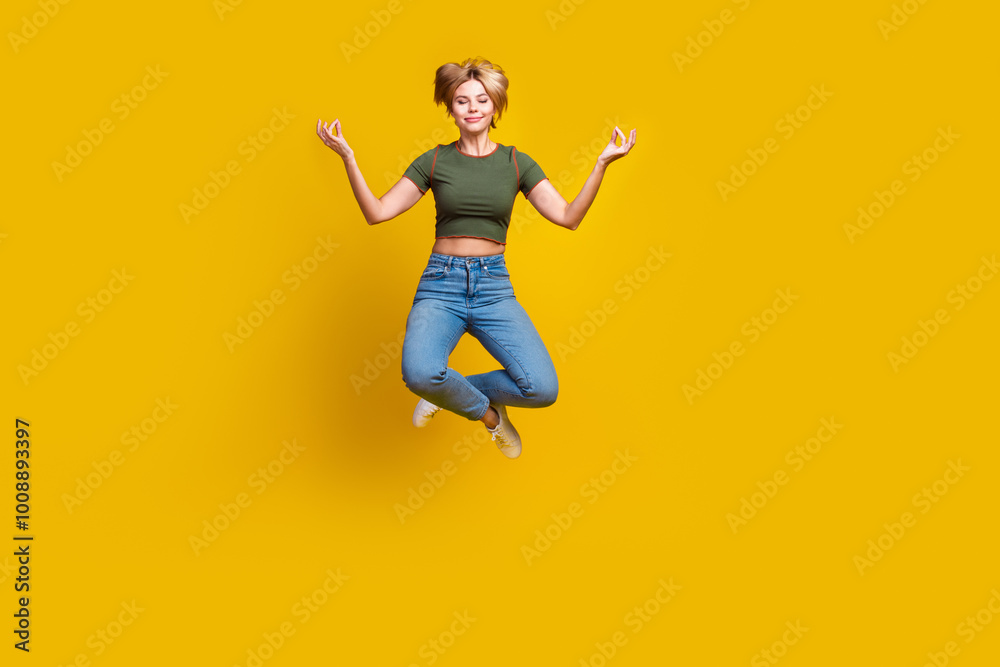 Full size photo of nice peaceful girl dressed khaki crop top jeans levitating in meditation pose isolated on yellow color background Full size photo of nice peaceful girl dressed khaki crop top jeans levitating in meditation pose isolated on yellow color background