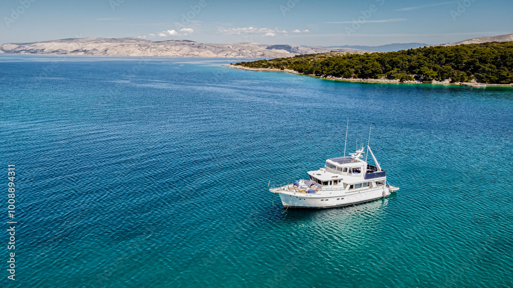 Obraz premium Aerial view from above of a large eco-friendly yacht with solar panels receiving energy during the day in the sea with clear, blue water. In the Mediterranean Sea. View from drone.