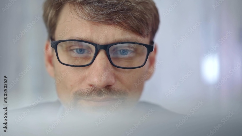 Businessman with glasses looking intently obscured partially by a translucent surface of laptop. Business concept Businessman with glasses looking intently obscured partially by a translucent surface of laptop. Business concept